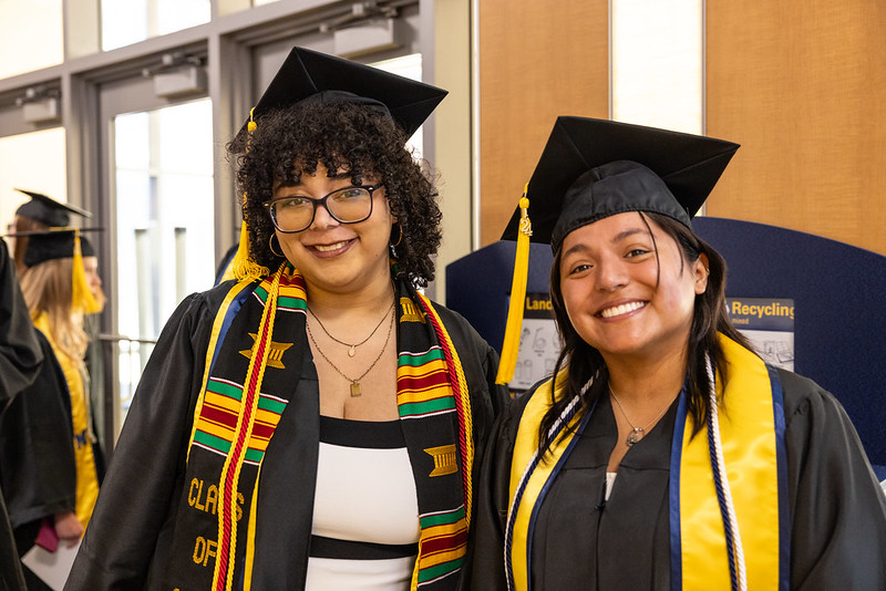 Two graduates in gowns smiling