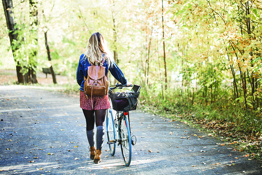 Woman walking with bike in woods